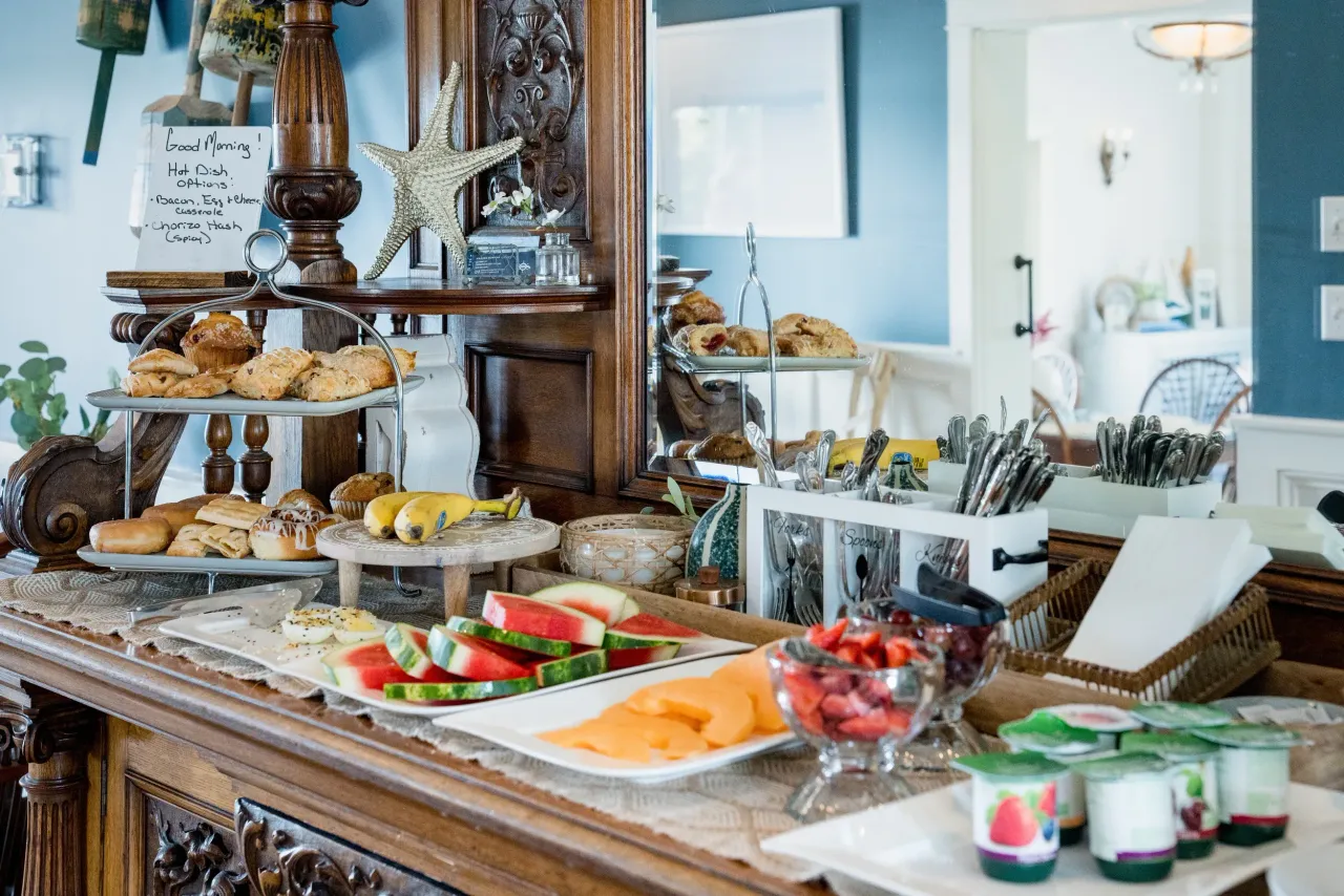 Buffet table with pastries, fruit, and yogurt in a bright dining room