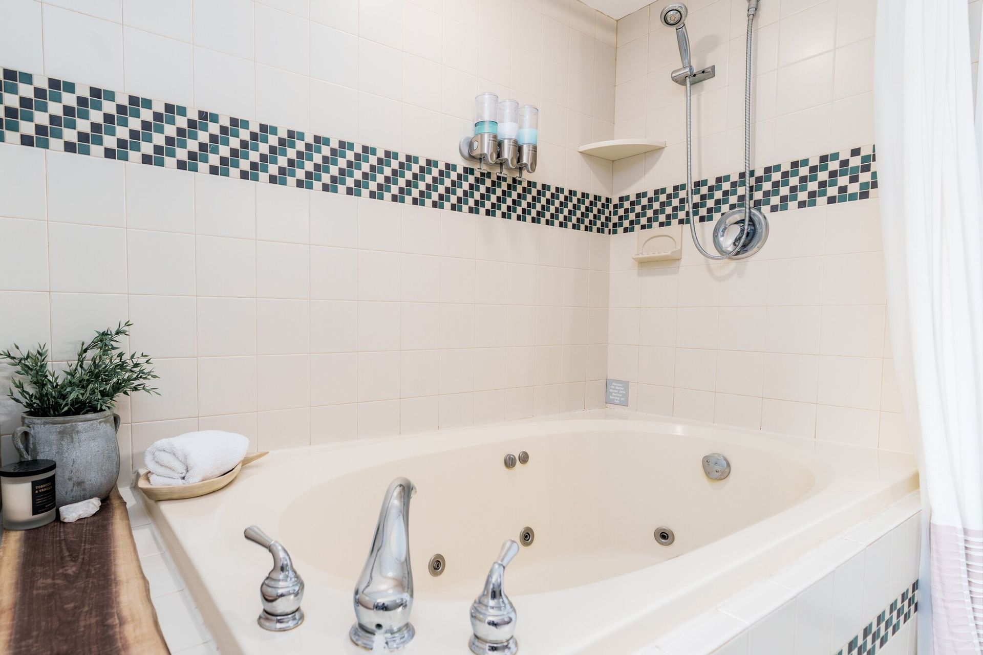 White bathroom with a corner bathtub, chrome fixtures, tiled walls, and plants on the ledge