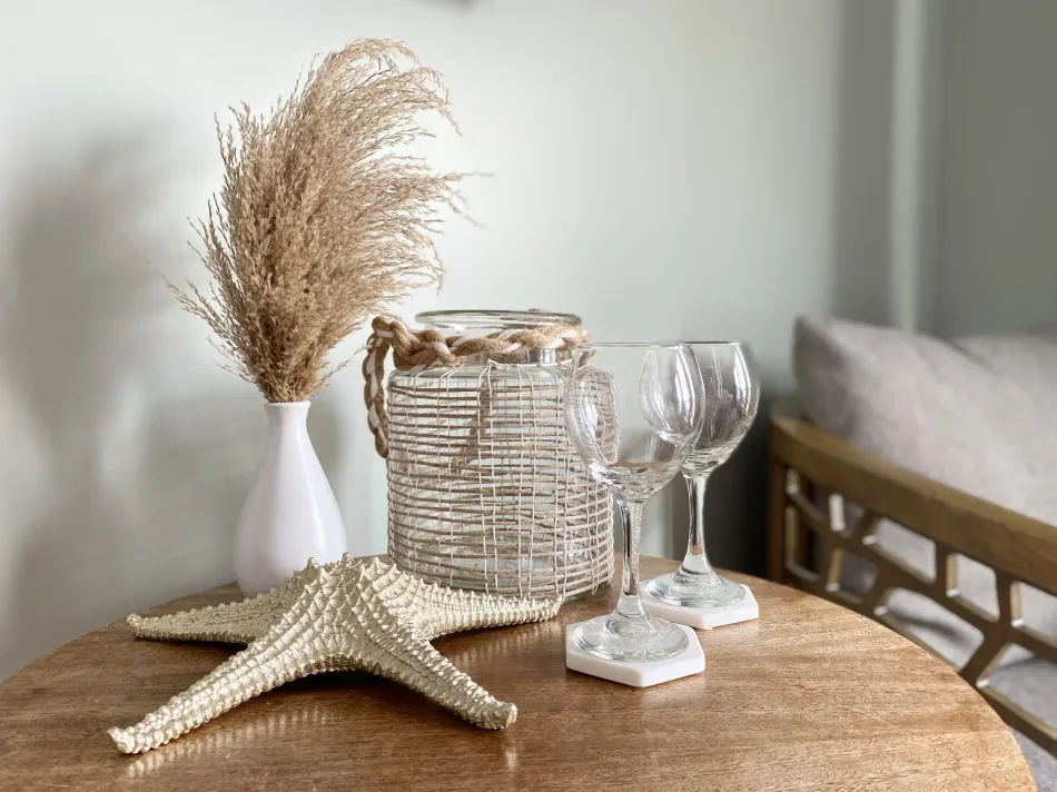 Coastal decor on a round wooden table with a starfish, glass vase, and goblet-style glasses