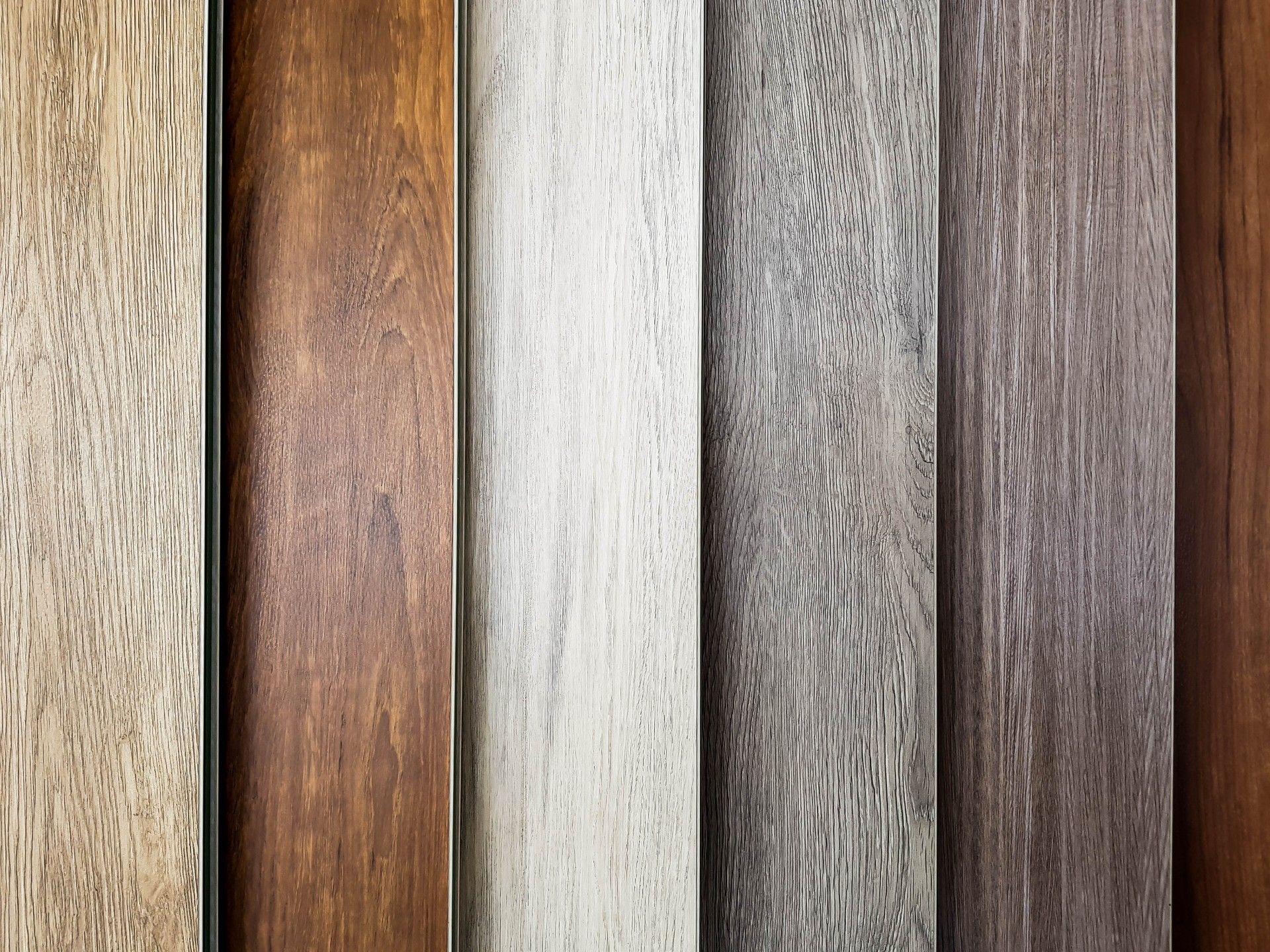 A collection of six vertical wood-look planks with varying textures and colors, ranging from light oak to dark brown.