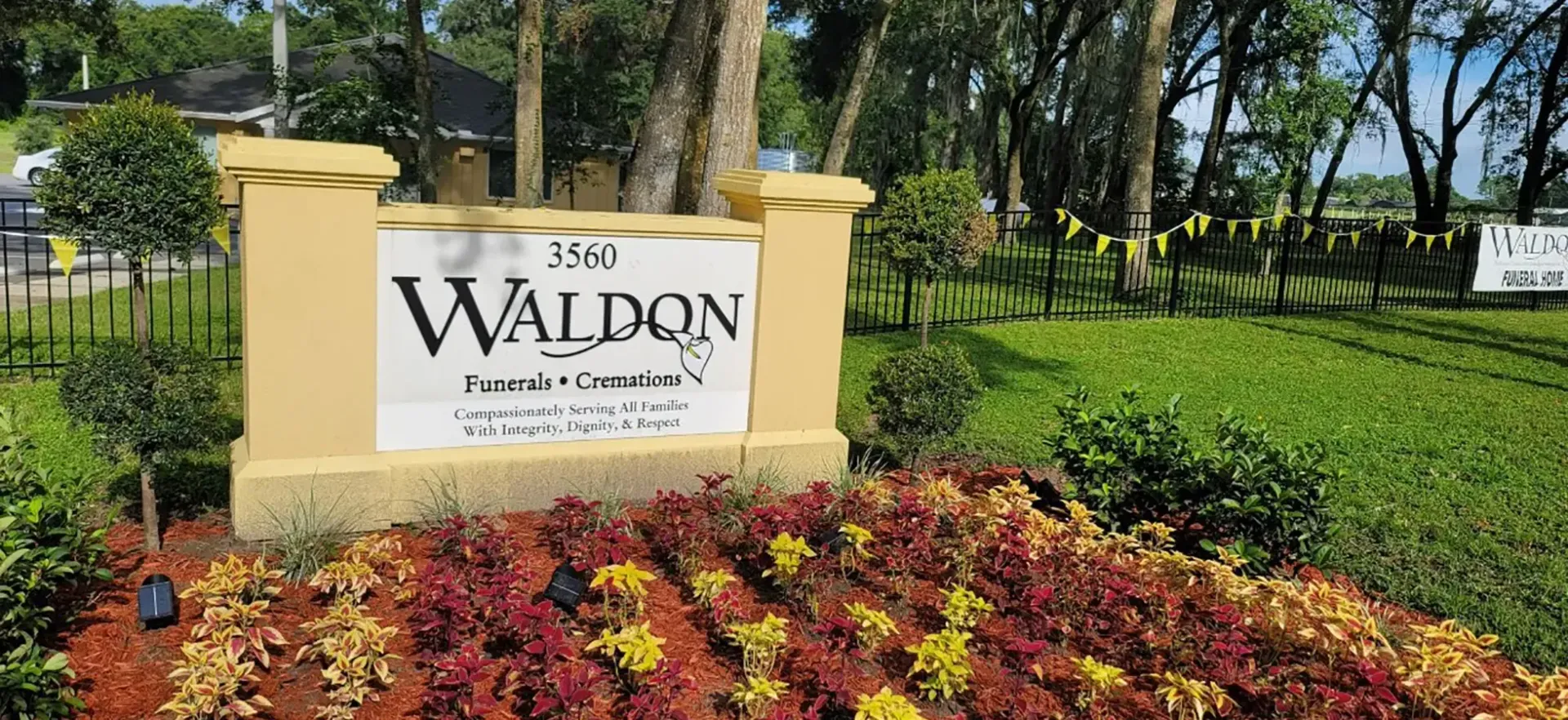 Walden entrance sign beside colorful flower bed and green lawn in a sunny park setting