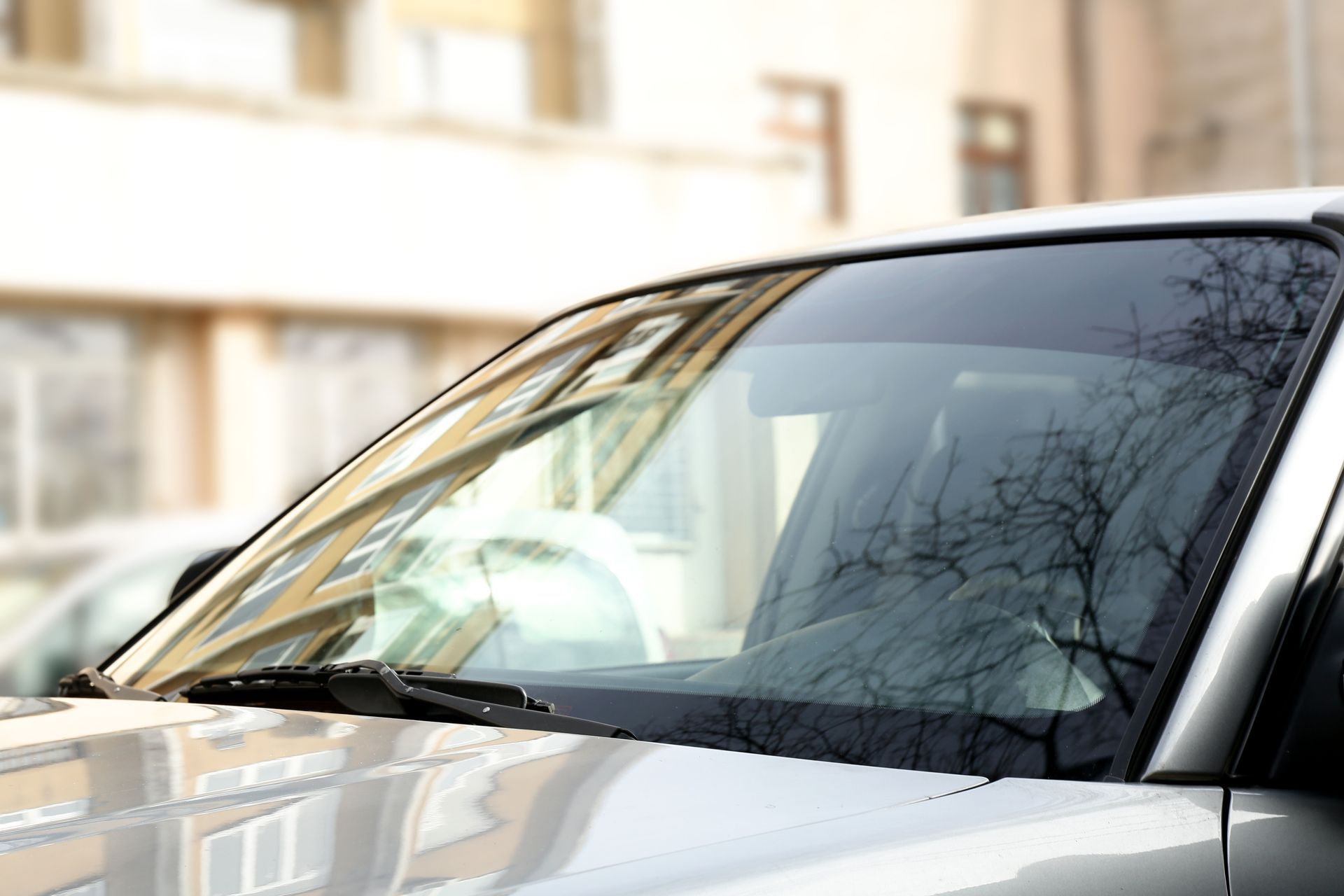 New windshield installed on a white vehicle with reflections of nearby buildings.