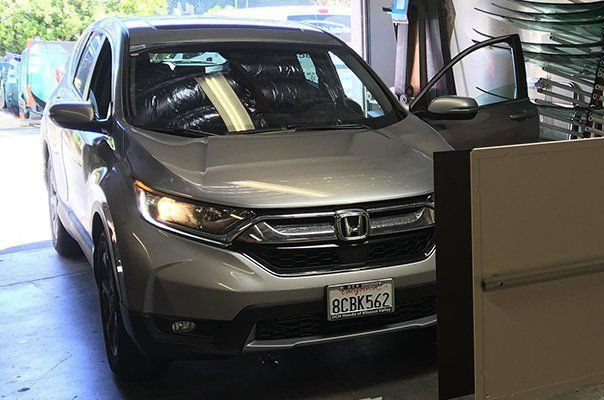 A silver honda cr v is parked in a garage. A silver honda cr v is parked in a garage.