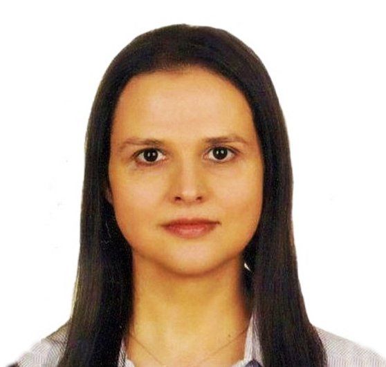 A woman with long dark hair is wearing a white shirt
