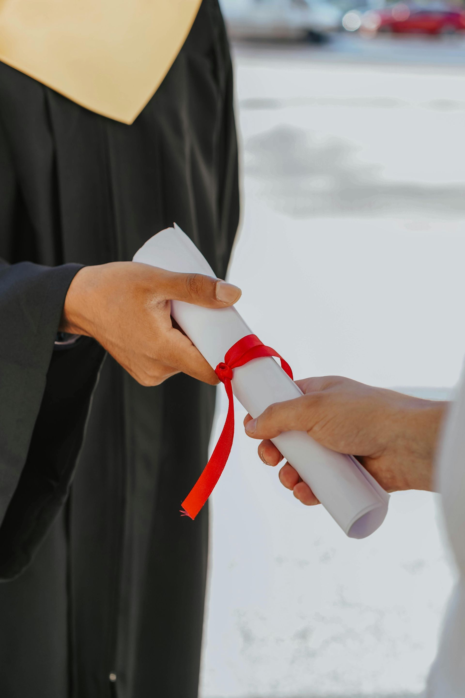 A graduate is handing a diploma to another person.