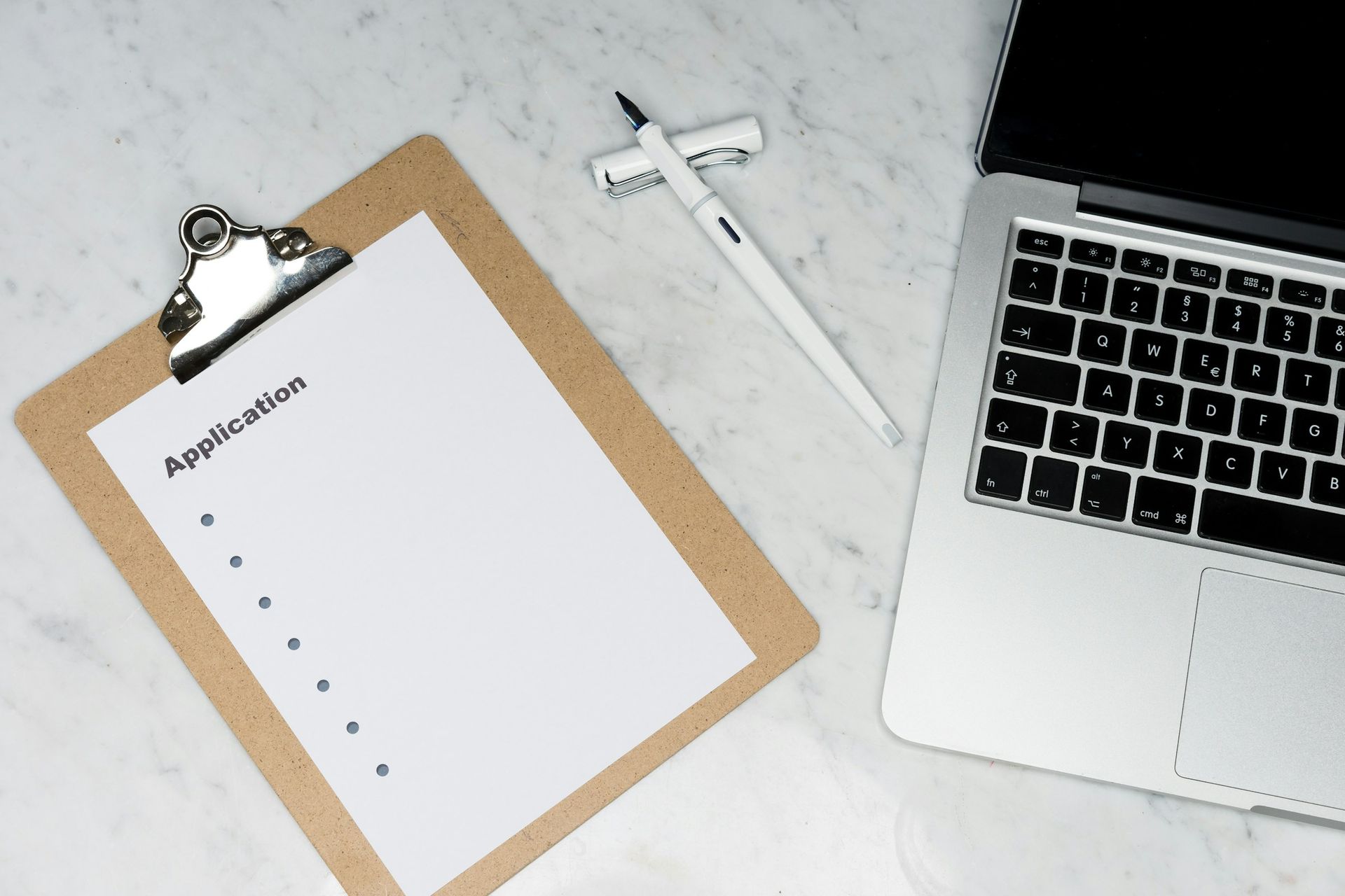 A clipboard with an application form, pen, and laptop on a desk, symbolizing scholarship preparation and application