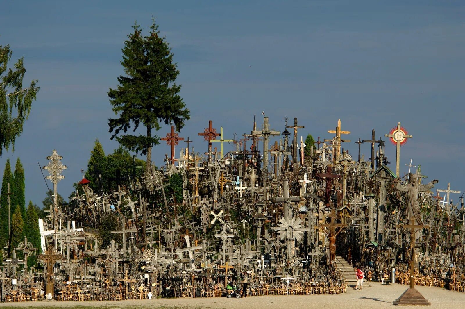 Hillside covered with hundreds of crosses and religious symbols under a blue sky