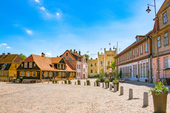 Sunny European cobblestone square with colorful historic buildings and flower planters