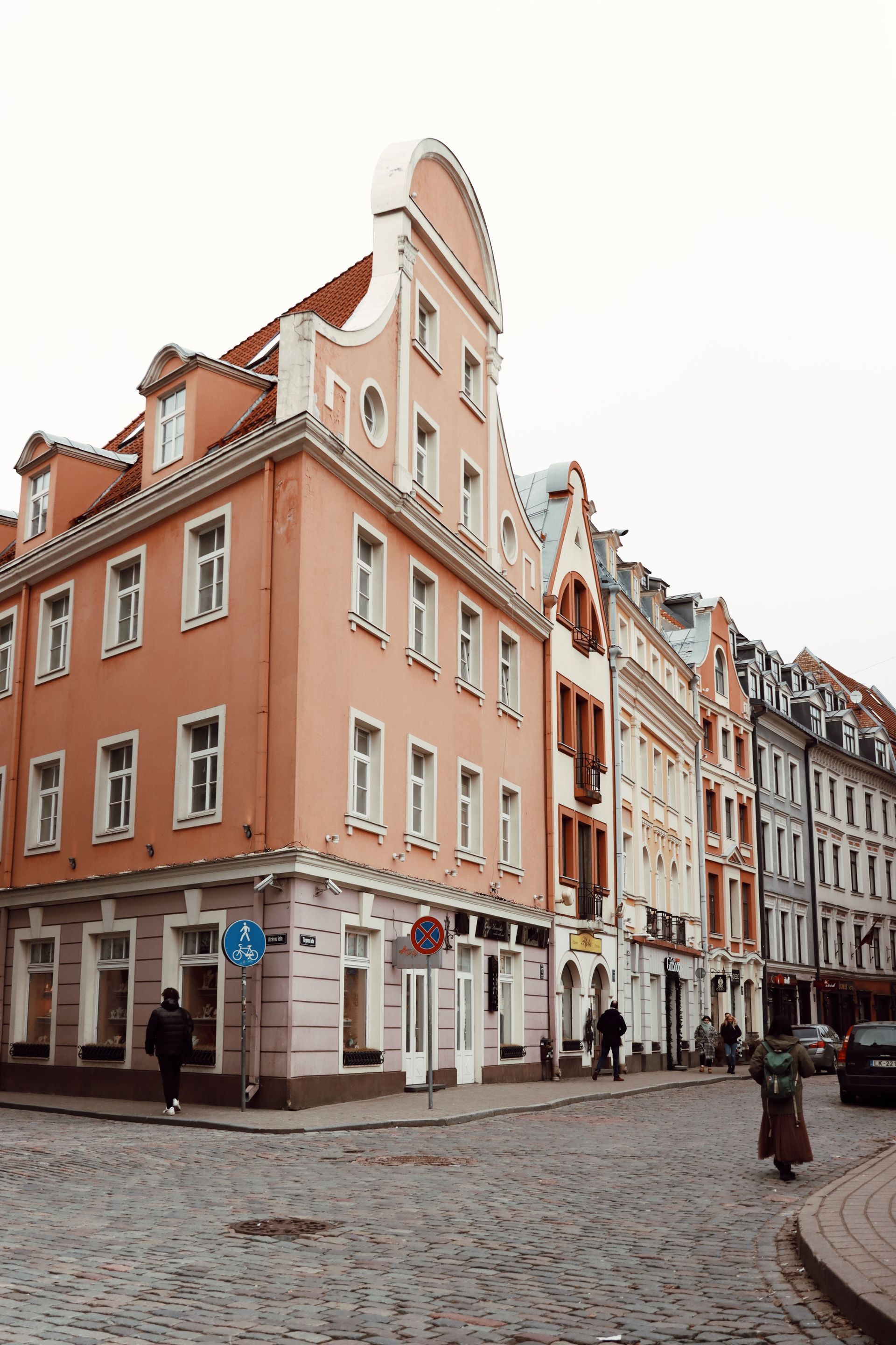 Cobblestone street lined with pastel historic buildings under an overcast sky