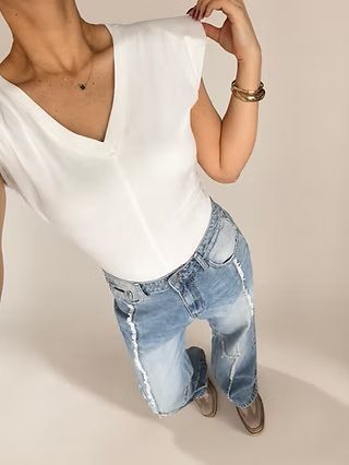 Persona con una camiseta blanca y vaqueros azules, fotografiada desde arriba.