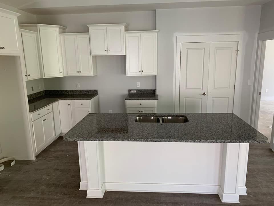 An empty kitchen with granite counter tops and white cabinets.