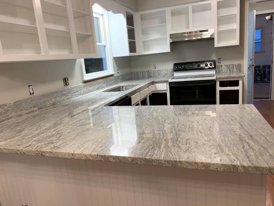 A kitchen with white cabinets and granite counter tops.