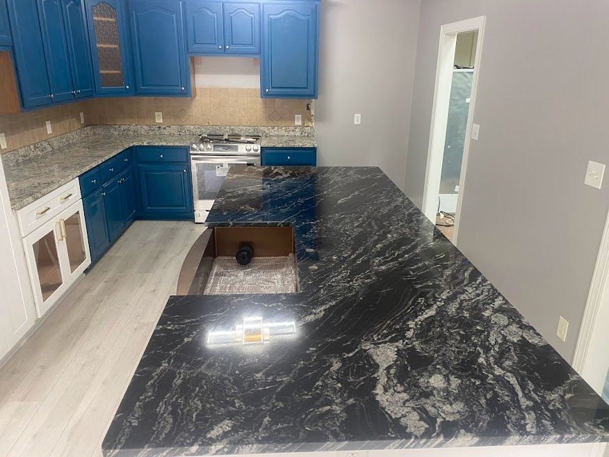 A kitchen with blue cabinets and black granite counter tops.