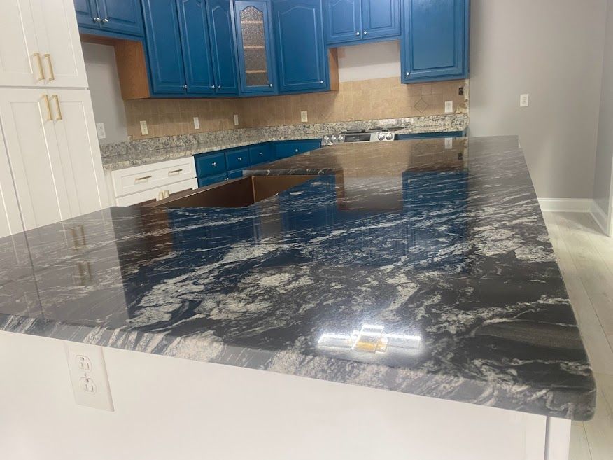 A kitchen with blue cabinets and a black granite counter top.