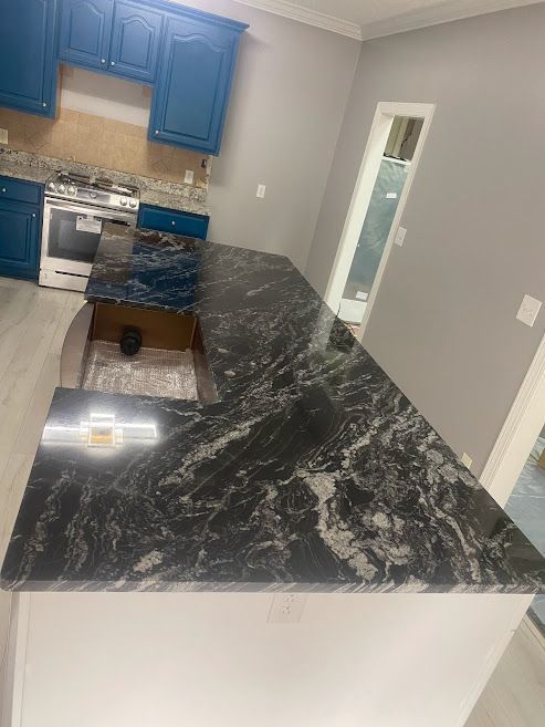 A kitchen with a black granite counter top and blue cabinets.