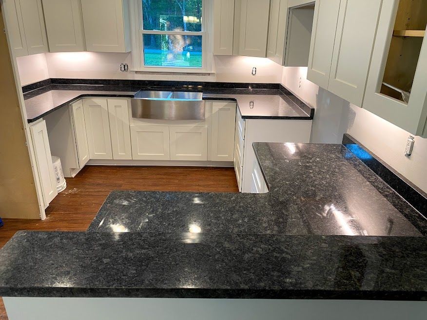 A kitchen with black granite counter tops and white cabinets