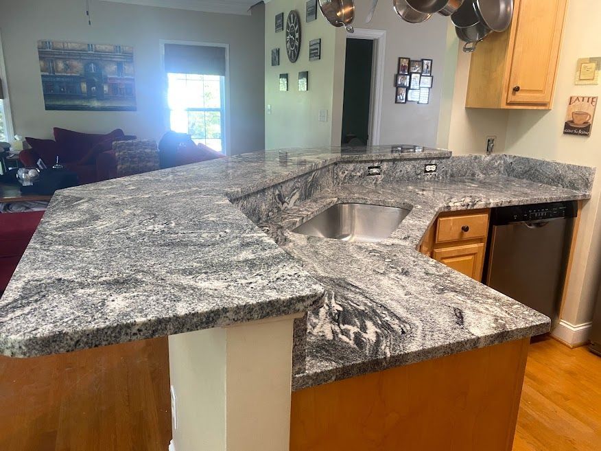 A kitchen with granite counter tops and a stainless steel sink.