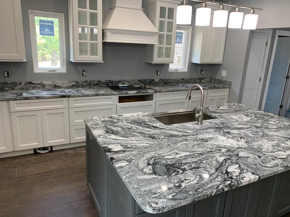 A kitchen with granite counter tops , white cabinets , and a sink.
