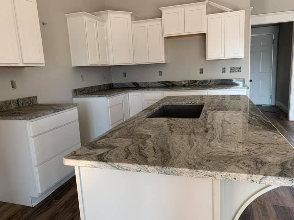 A kitchen with granite counter tops and white cabinets.