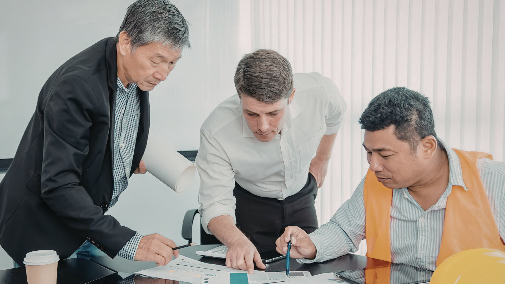 Three men reviewing plans and documents together at a work table
