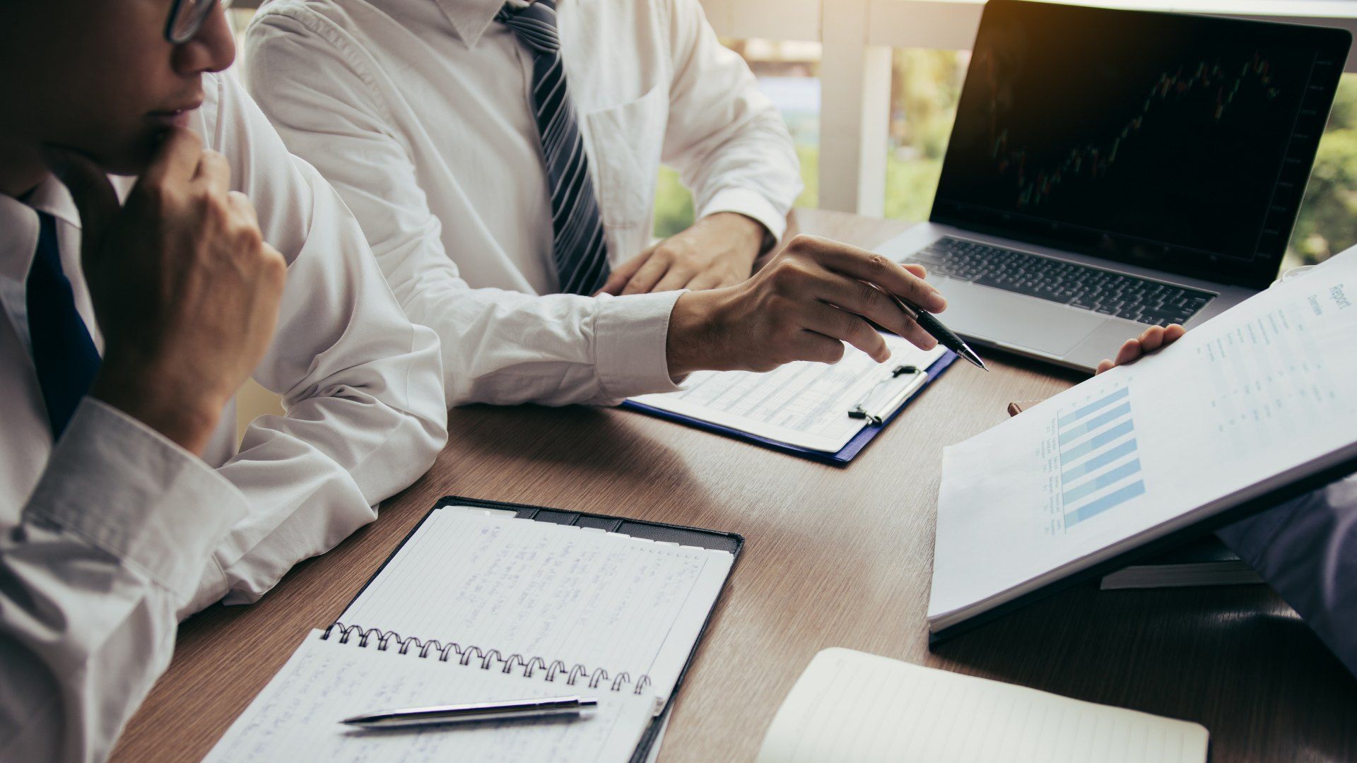 Two professionals reviewing documents and a laptop at a conference table