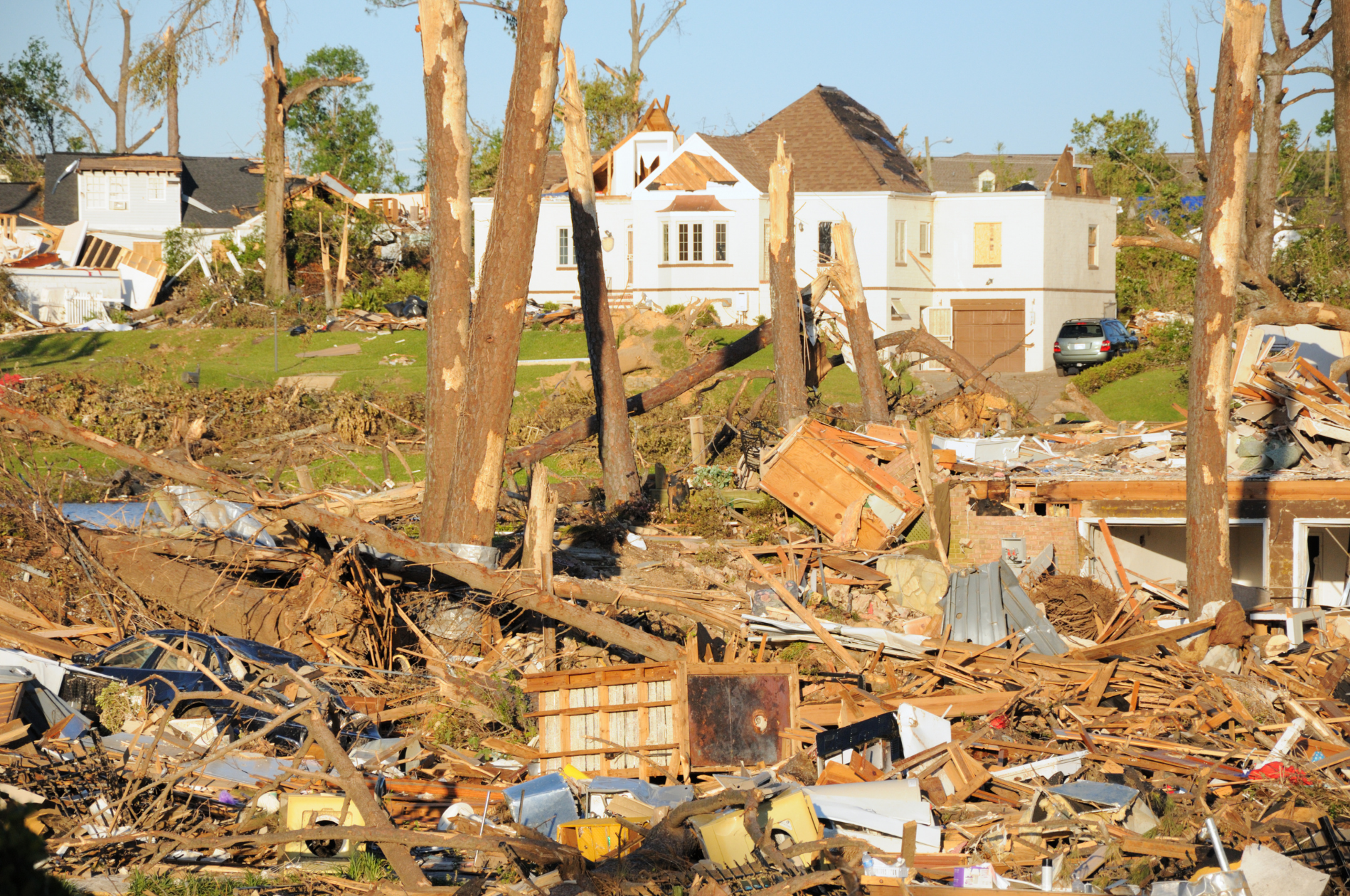 Storm damage with debris scattered across a neighborhood and damaged houses in the background