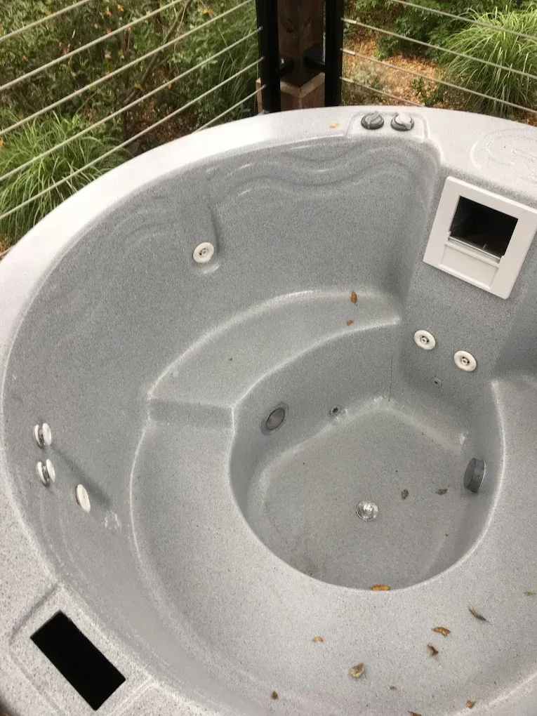 Gray outdoor hot tub with seats and control panel, viewed from above