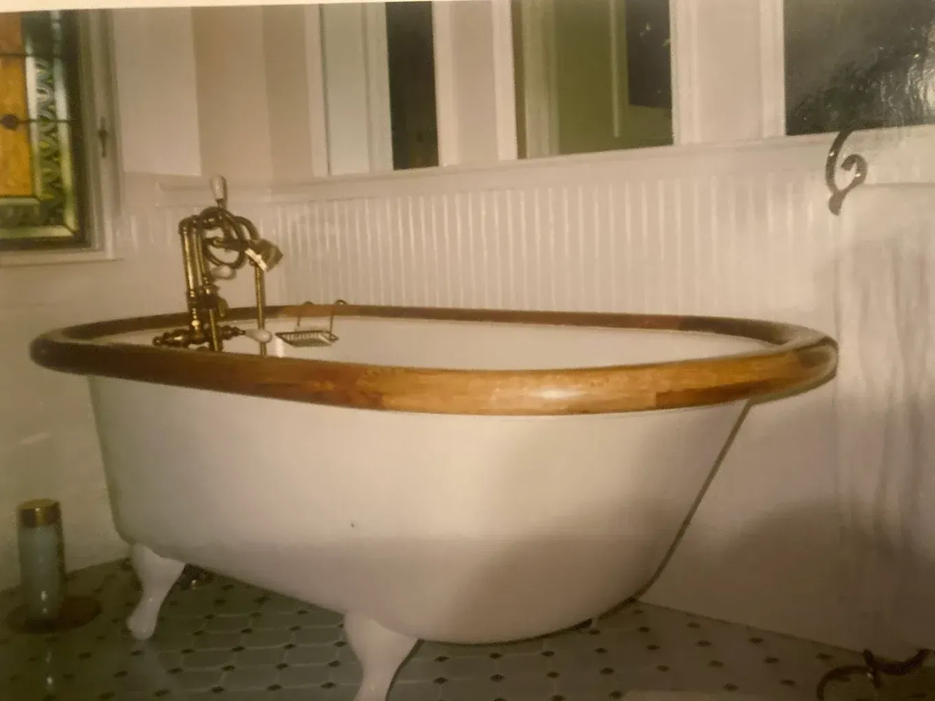 Vintage clawfoot bathtub with brass fixtures in a white-tiled bathroom