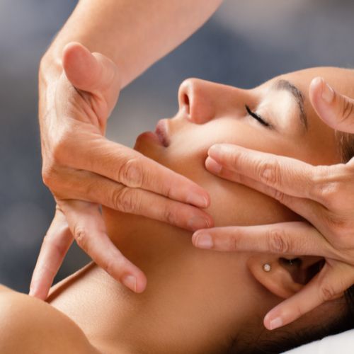Woman receiving a facial at a spa; eyes closed, relaxed. Attendant with gloves.