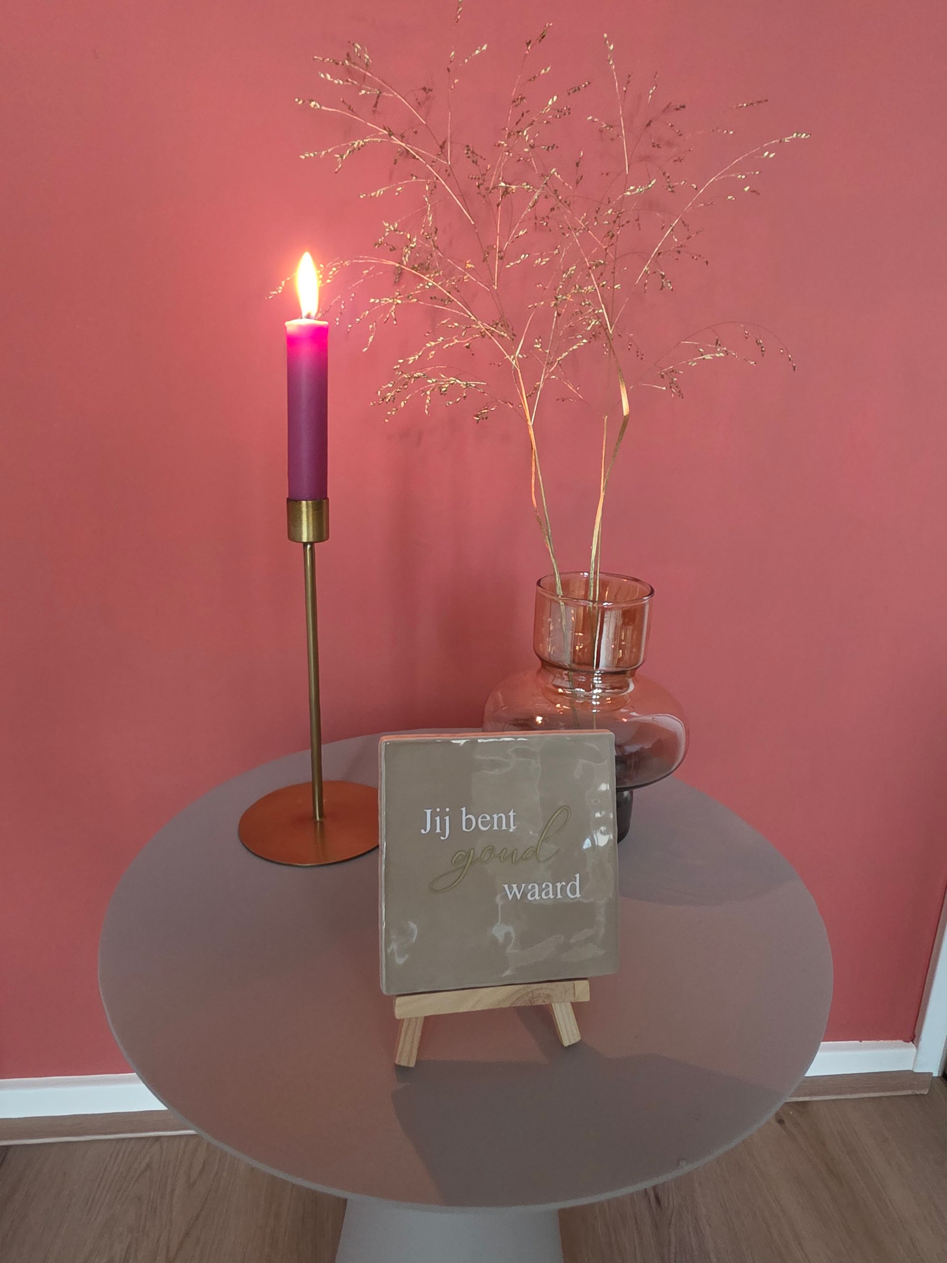 Tafelscène met een brandende kaars, een gouden tak en een bordje met de tekst 