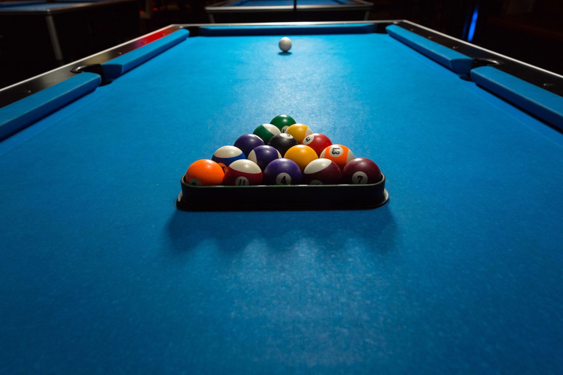 Pool table with a racked set of billiard balls and cue ball on blue felt