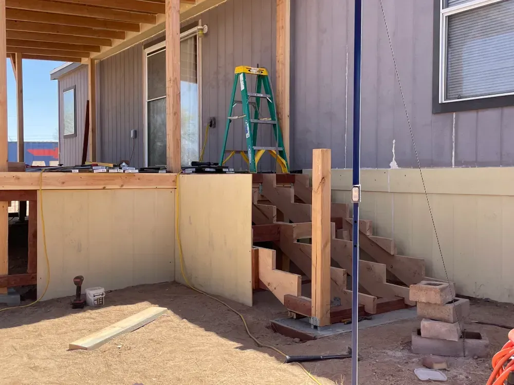 Wooden stairs under construction leading to a deck on a house.