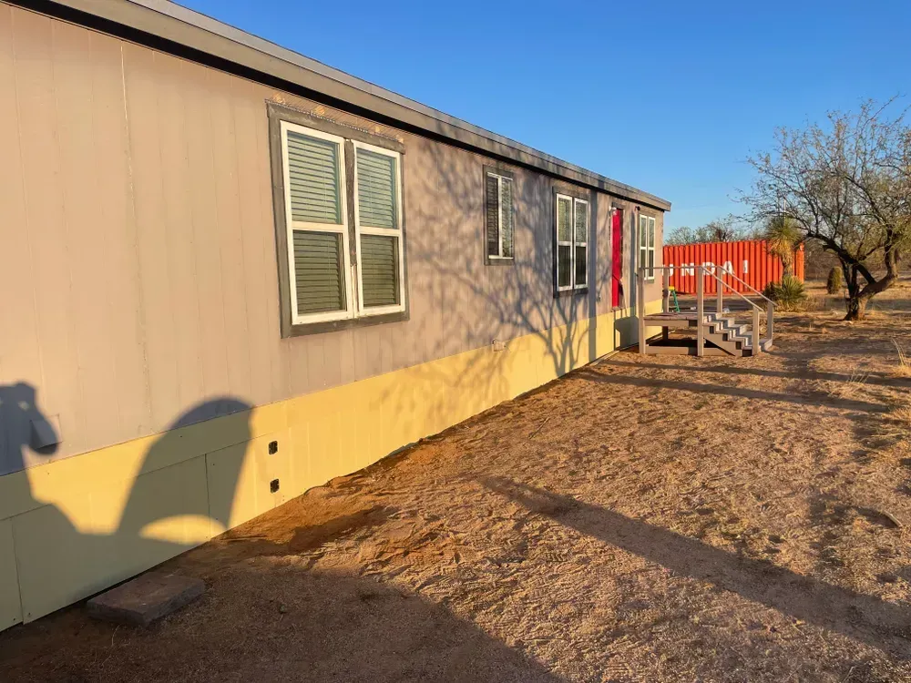 Mobile home exterior with yellow and gray siding, windows, and a red door.