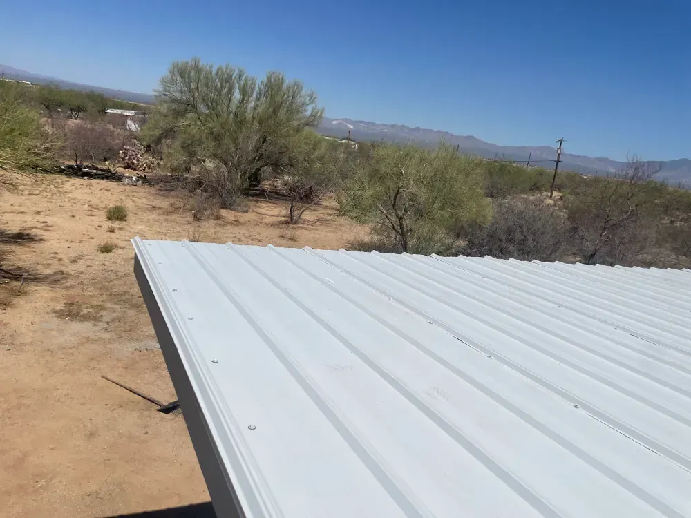 White metal roof edge with a desert landscape background under a bright blue sky.