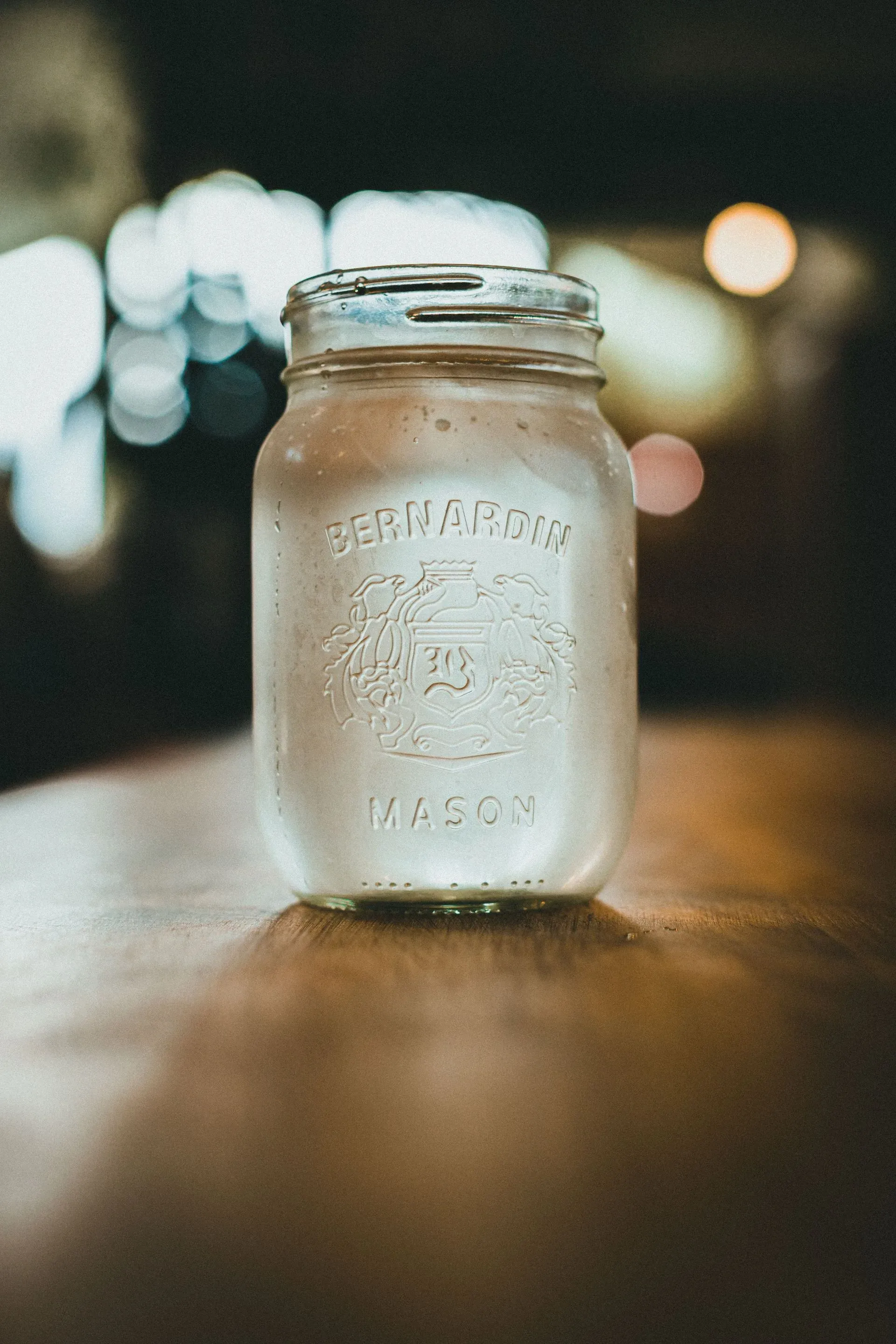 A glass mason jar of water on a wooden table