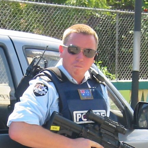 Man in light blue uniform with black tie, smiling.