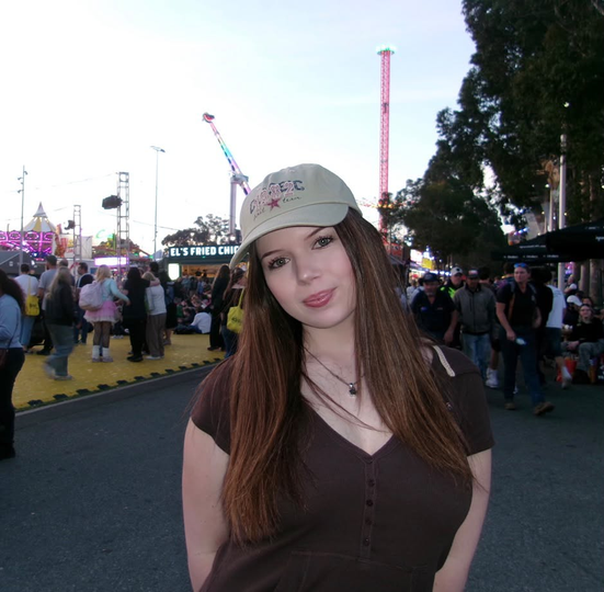 Woman with brown hair, streaks of blonde, looking directly at the camera with a neutral expression. Outdoors, sunny day.