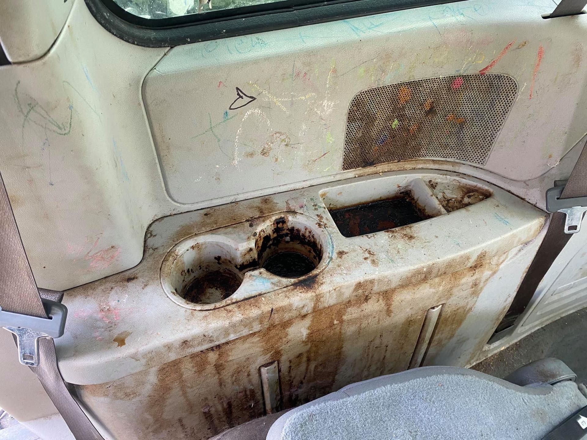 Dirty vehicle interior panel with cup holders and a small storage compartment