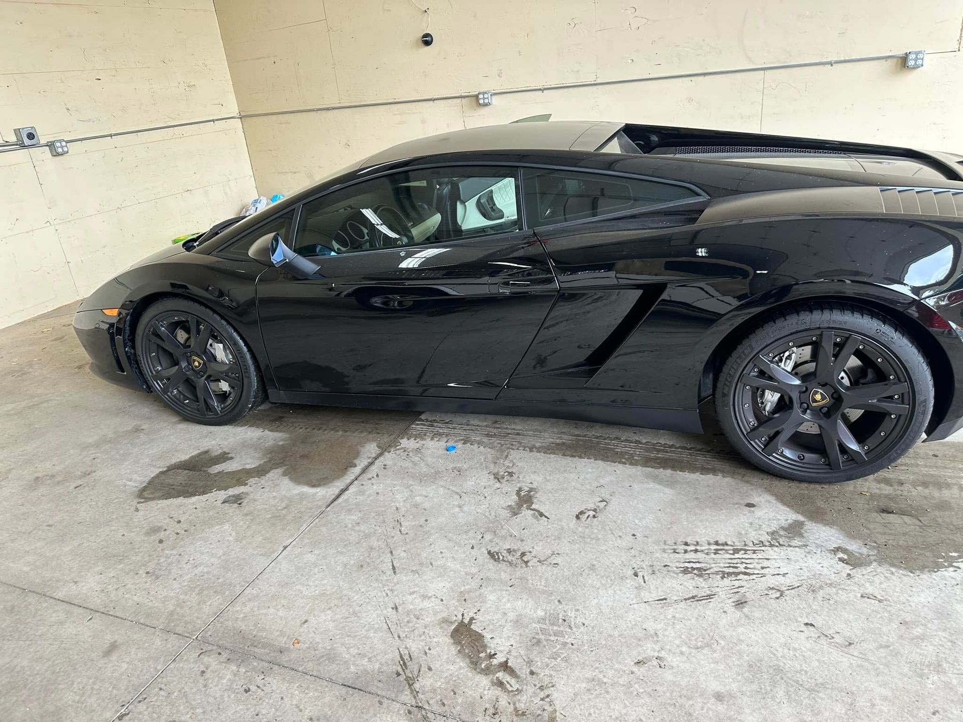 Black sports car parked indoors in a garage, side view.