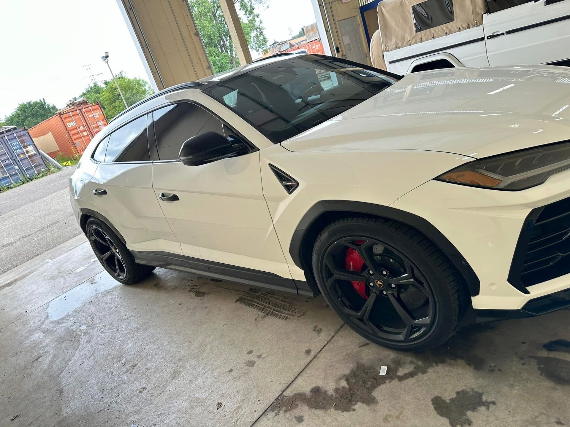 White sports SUV with black rims parked in a wet driveway under a covered area.