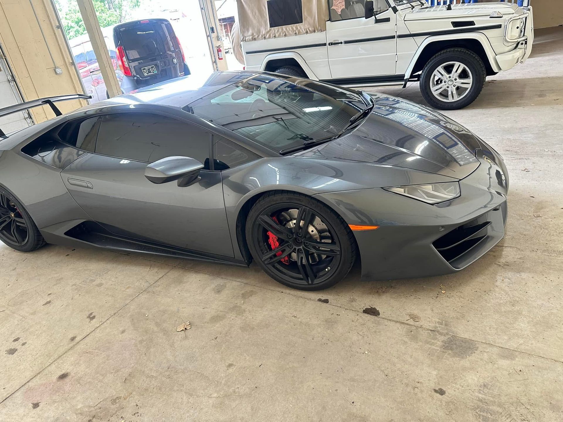 Gray Lamborghini coupe parked in a garage, viewed from the front-left side