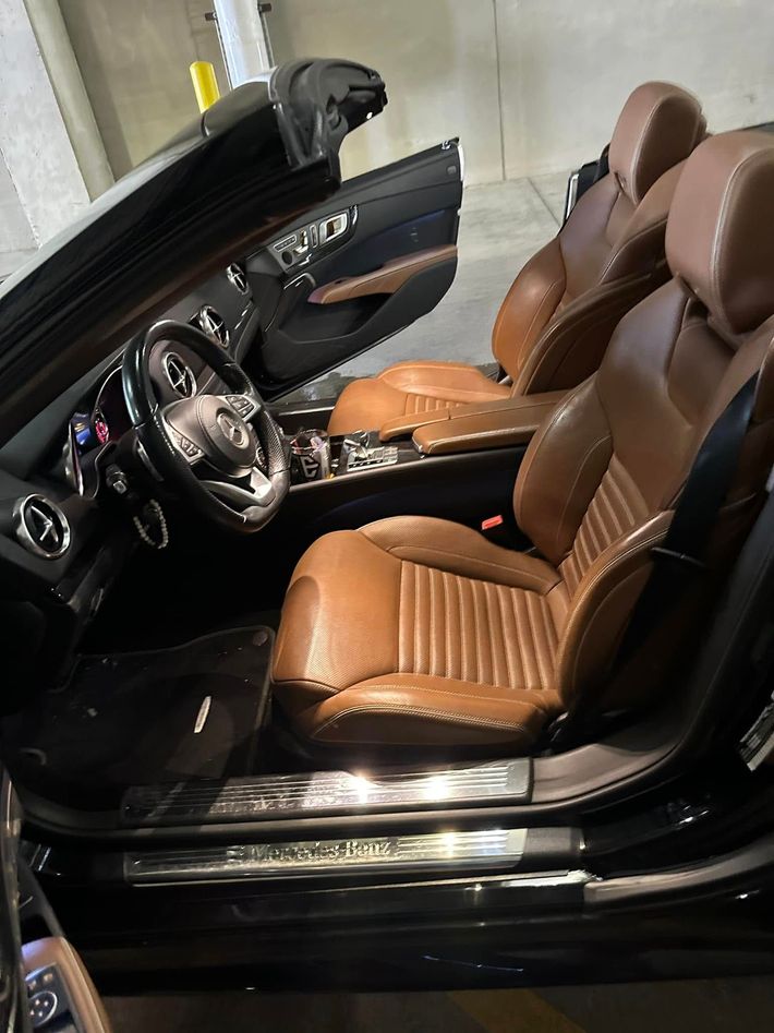 Black convertible interior with tan leather seats and dashboard, shown from the open driver’s side.
