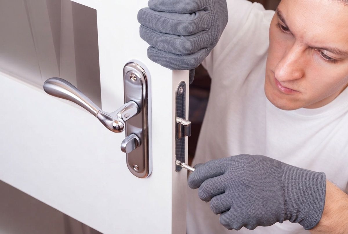 A professional technician in a white shirt and gray work gloves repairing a door lock in Fairfield, CA
