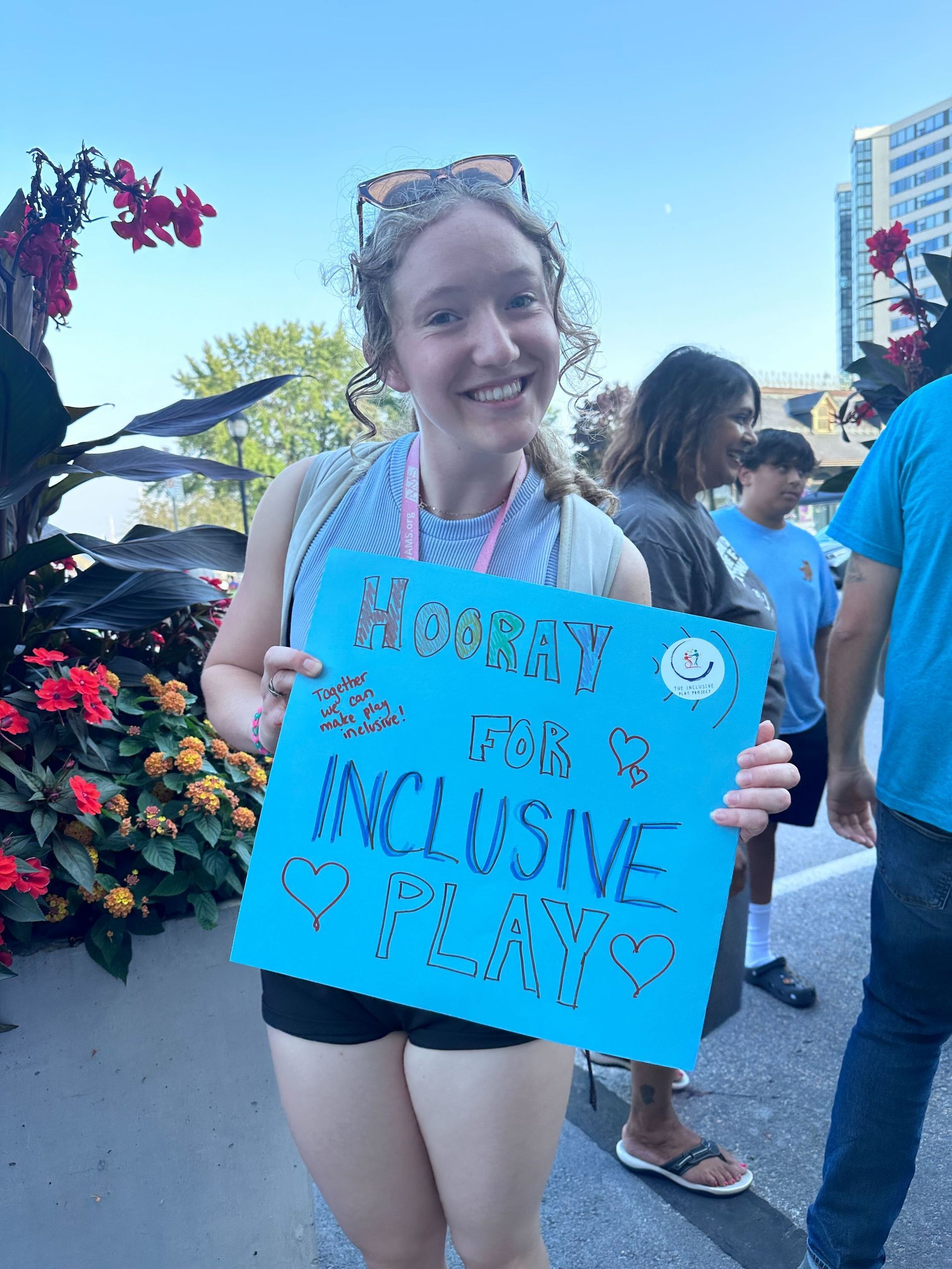 A woman is holding a sign that says inclusive play