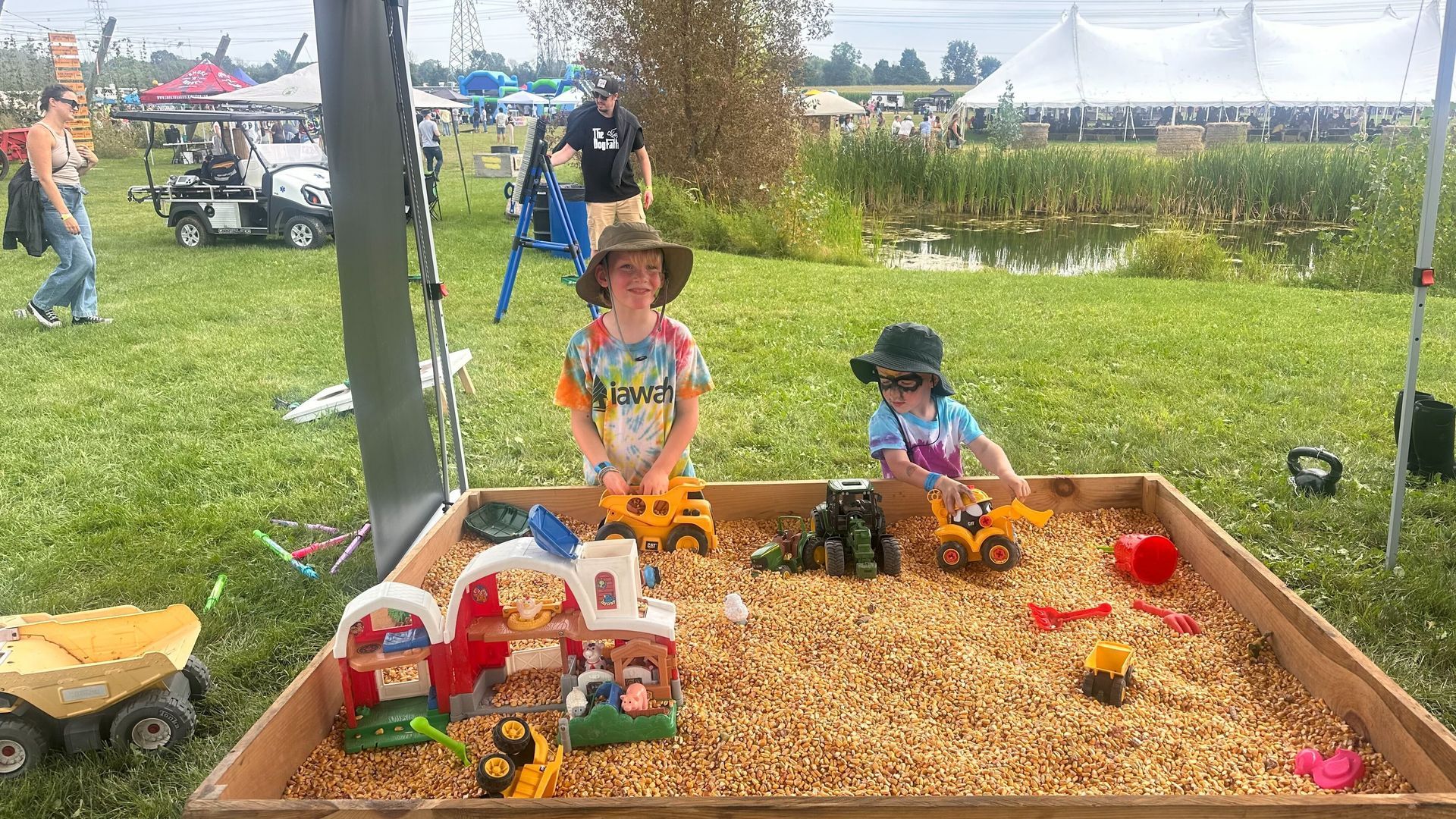 Two children are playing in a sandbox filled with toys.