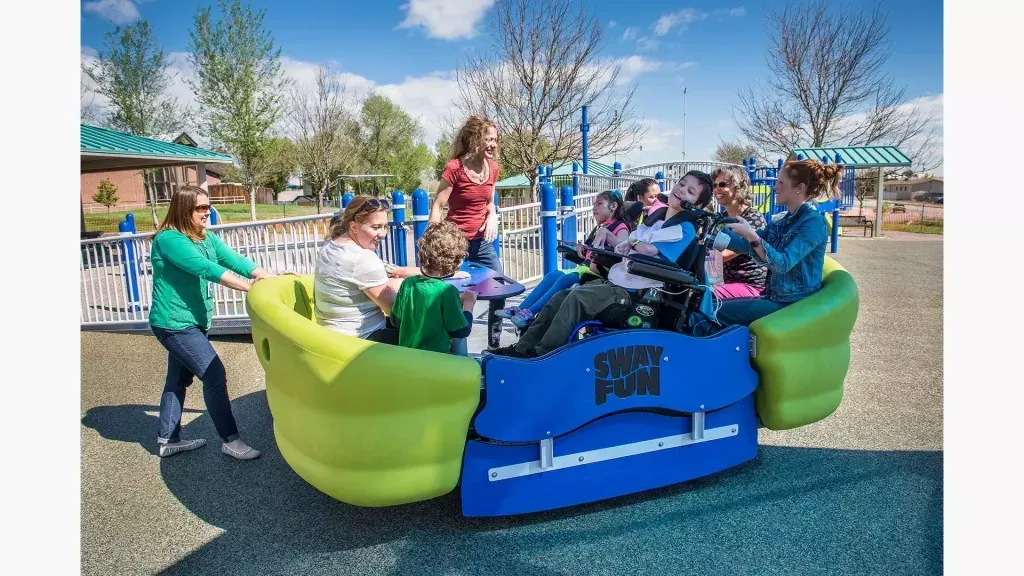 A group of people are riding a roundabout in a park.