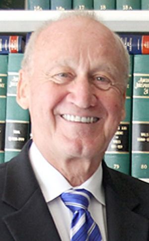 Smiling man in suit and striped tie in front of bookshelves