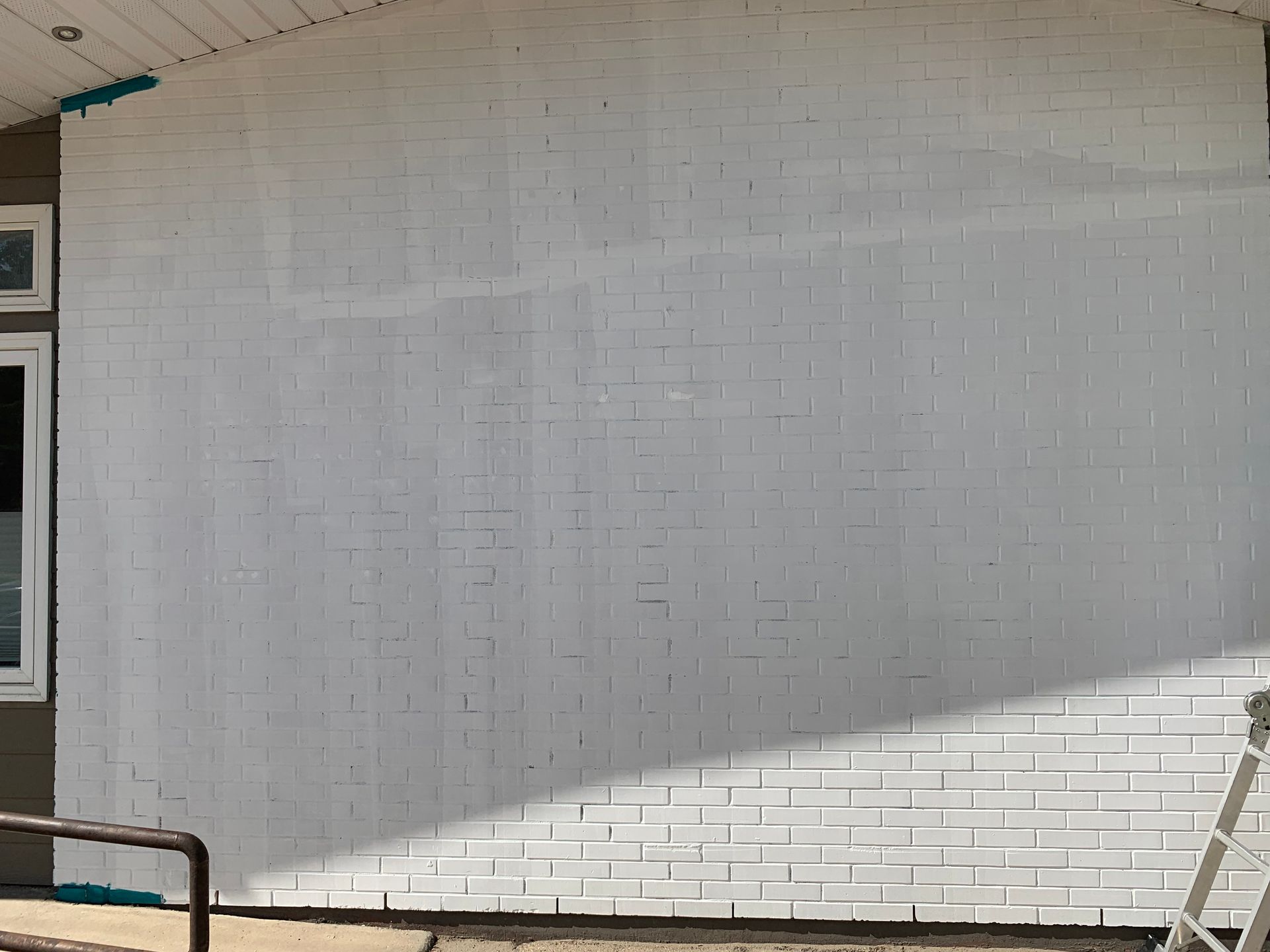 White brick wall with a large blank mural and diagonal shadow outdoors