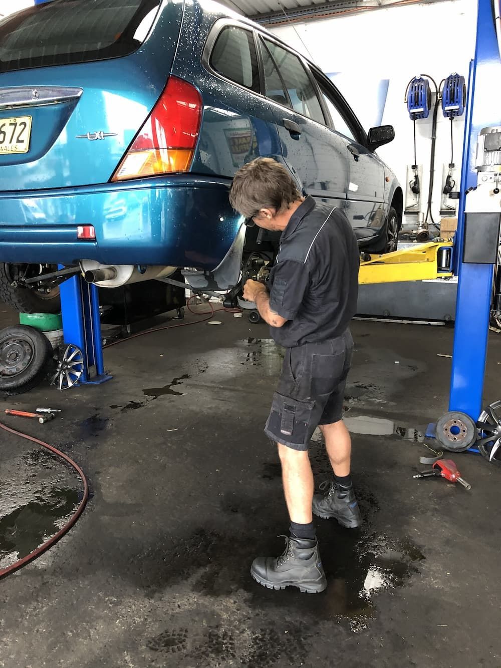 A Man Is Working on A Blue Car in A Garage — GT Auto Center in Tweed Heads South, NSW