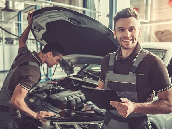 Two Mechanics Are Working on A Car in A Garage and One Is Holding a Clipboard — GT Auto Center in Tweed Heads South, NSW
